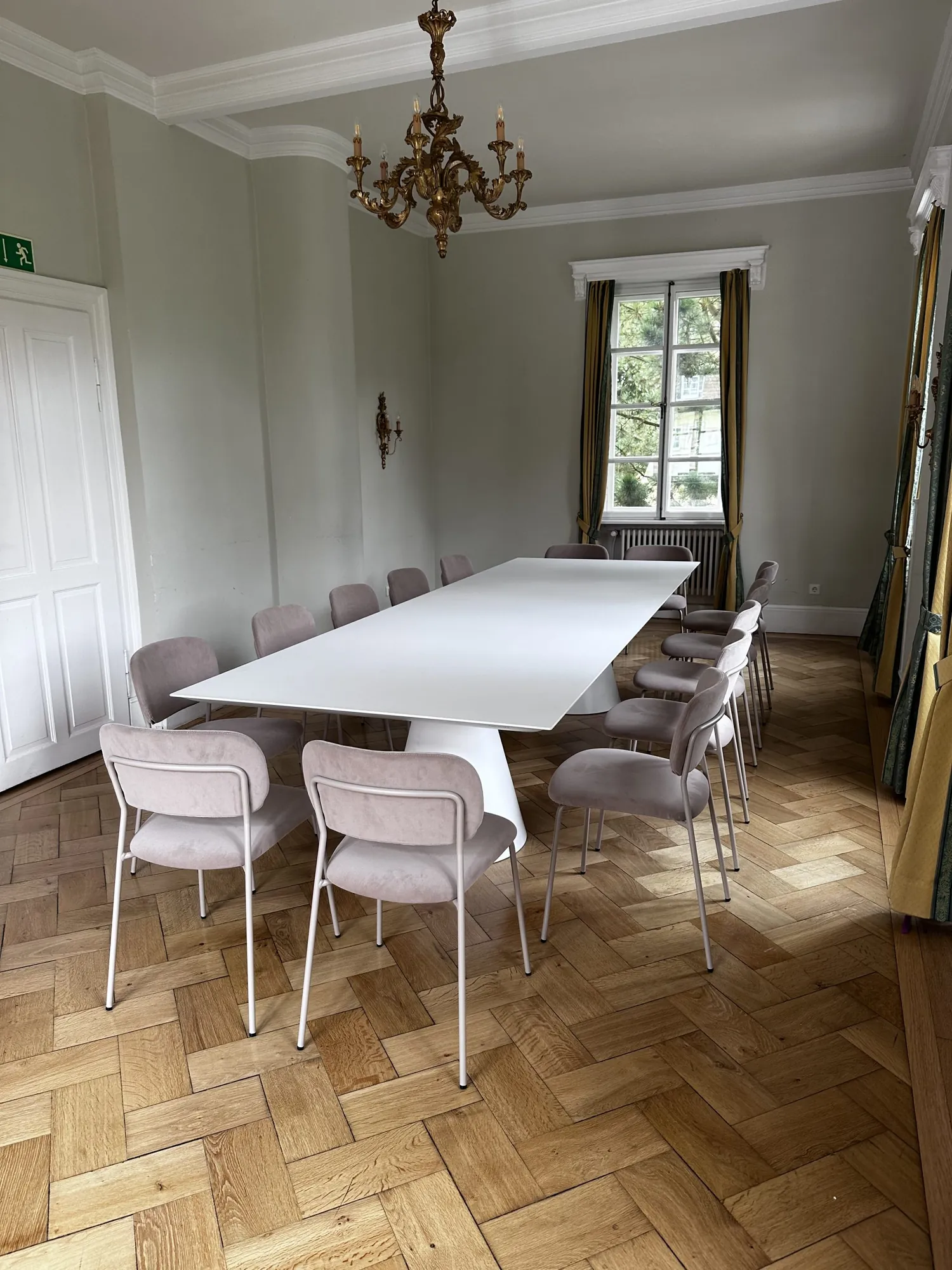 Besprechungsraum mit langem weißem Tisch, Stühlen und Kronleuchter